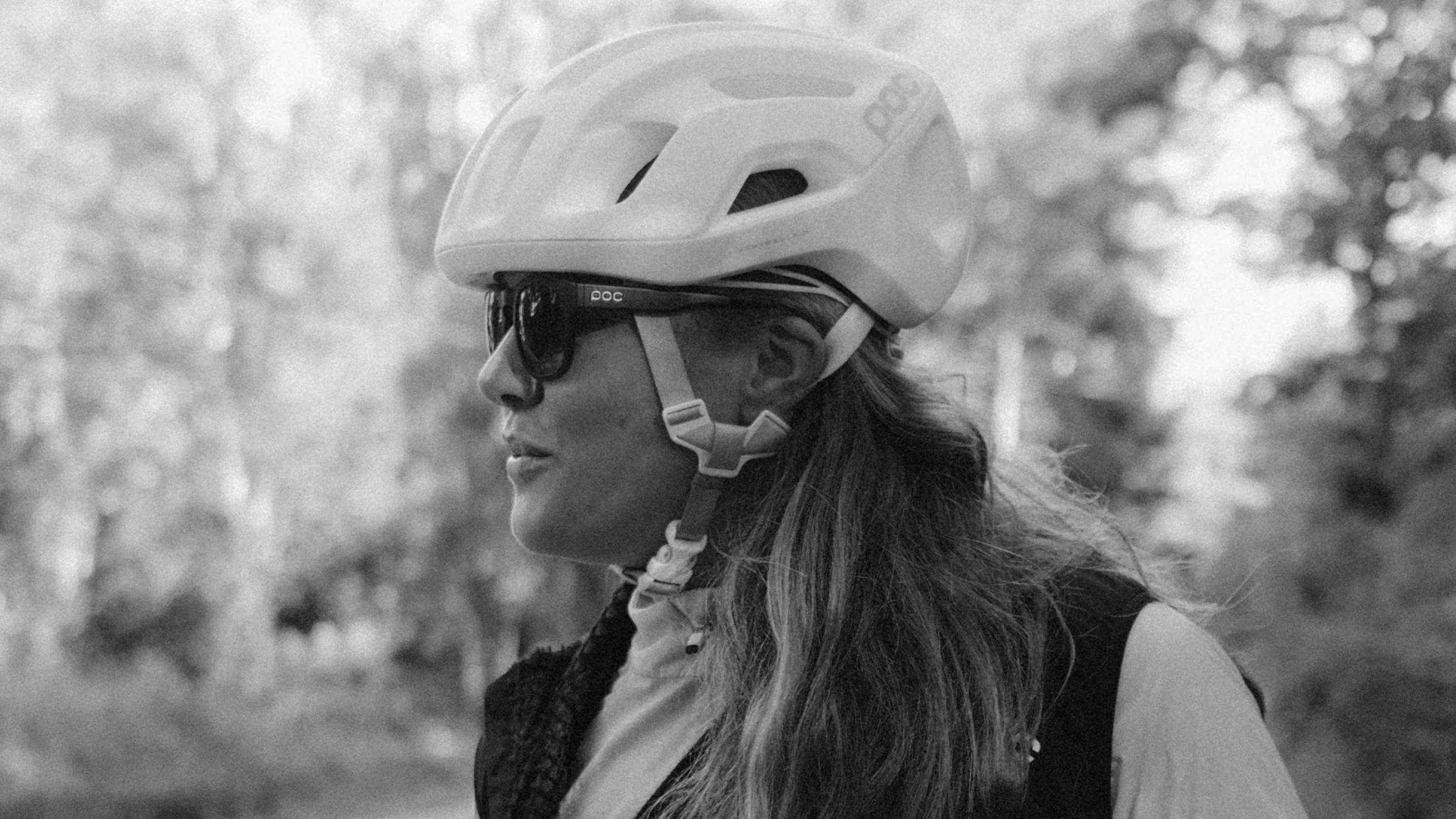 Ljushårig Kvinna med solglassögon och cykelhjälm kollar åt vänster