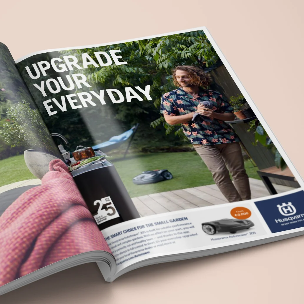 Mockup av en tidning, "uppgrade your everyday" syns uppslaget tillsammans med liten Husqvarna logga samt en man som håller i en handduk