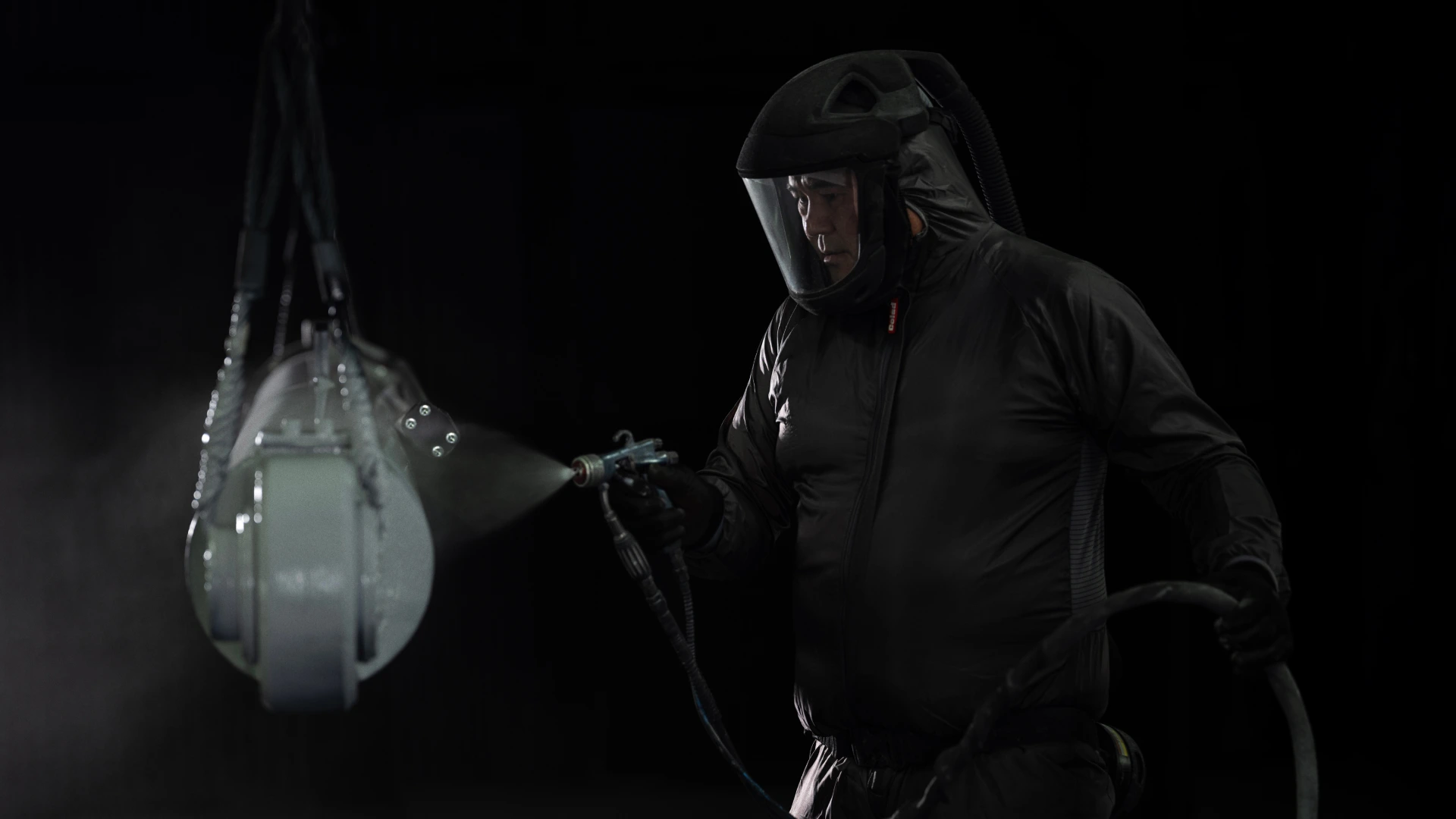 Man spray painting a cylinder grey