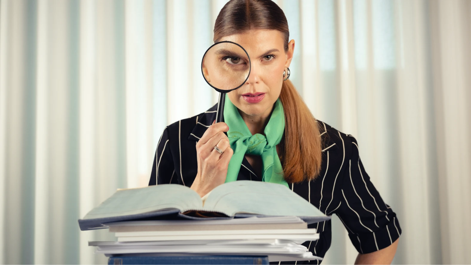 Lasia – Arbetsrätt för alla. Kvinna som tittar in i kameran genom att förstoringsglas med papper framför sig.
