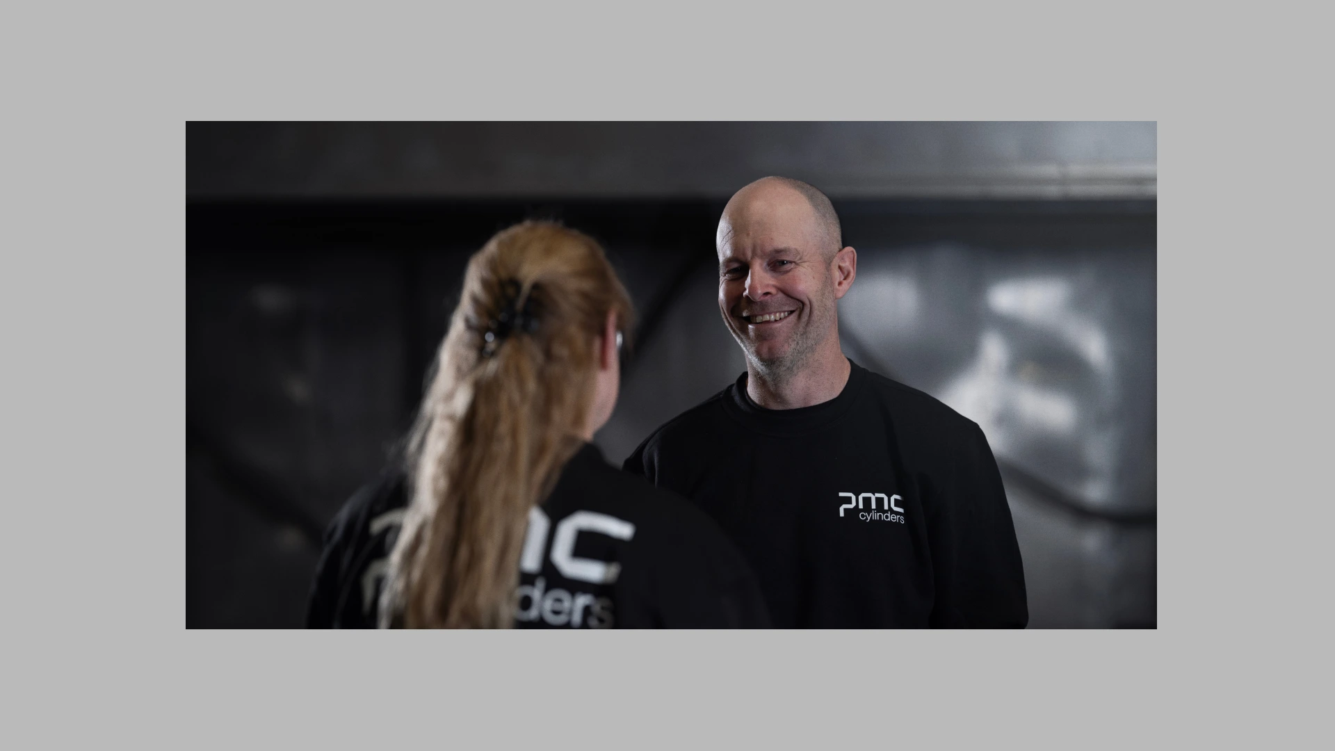 Two people talking with PMC t-shirts