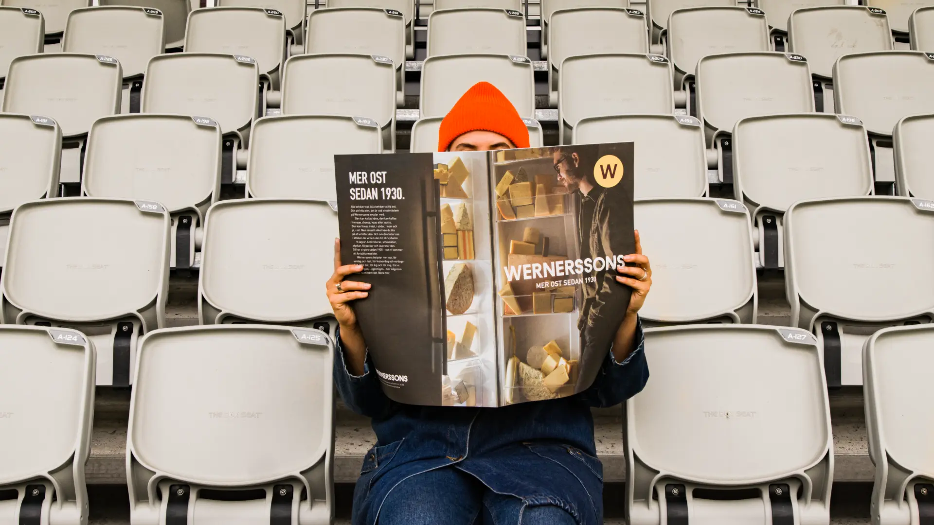 Person som sitter på en läktare och läser Wernerssons tidning - Ny Studio