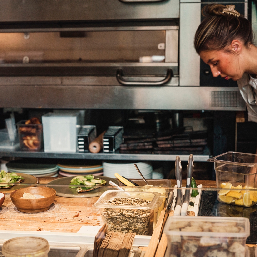 Kvinna i restaurangkök som lägger upp varor på disken - Ny Studio