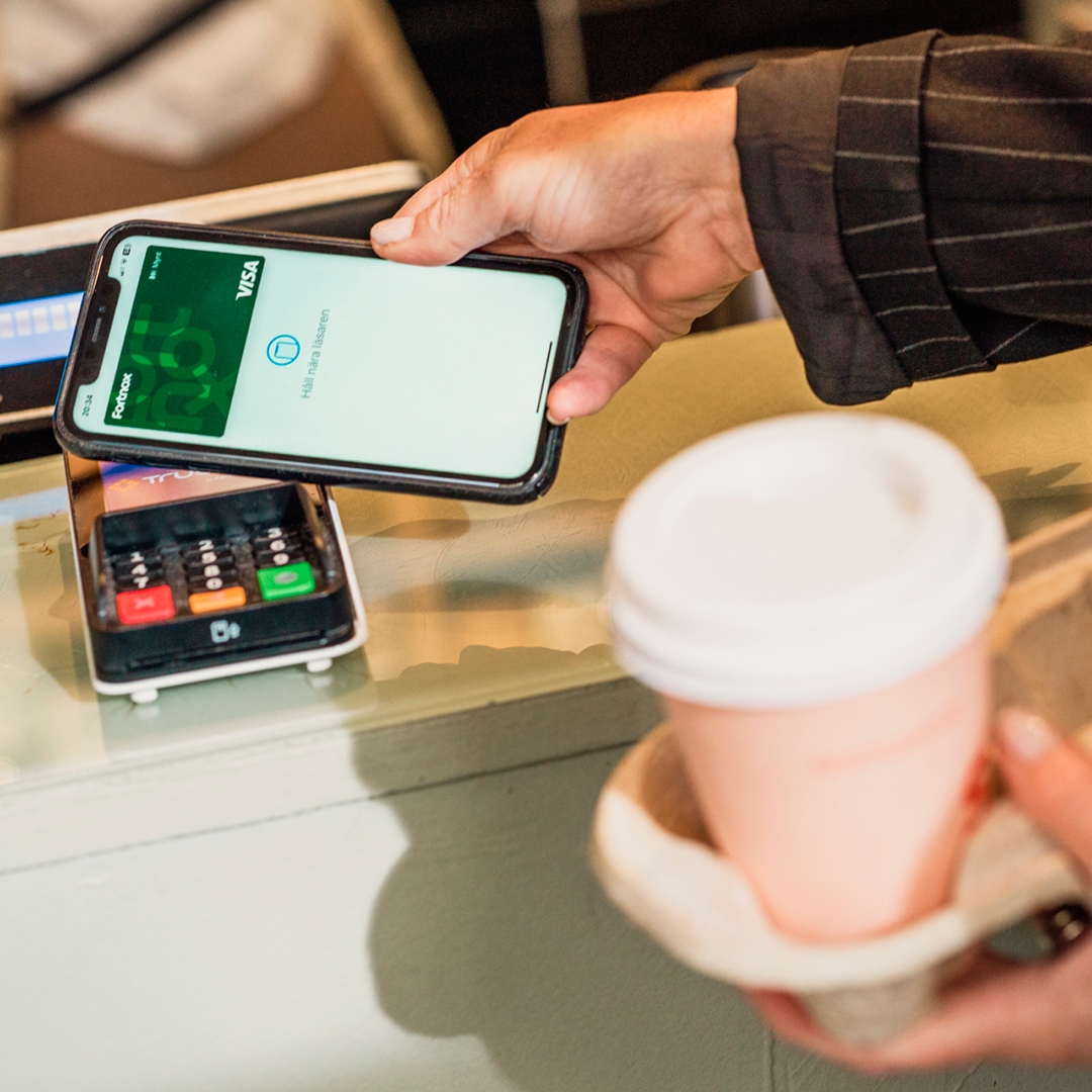Person som betalar med mobilen på en kortläsare hållandes i en kaffemugg - Ny Studio
