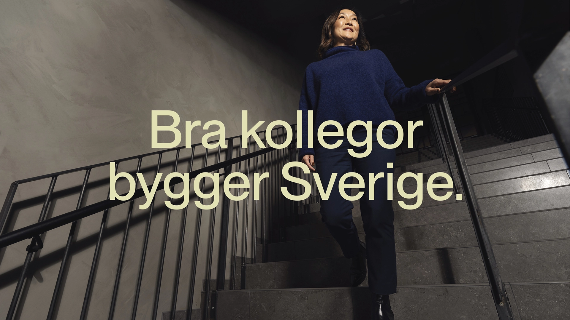 Kvinna går ned för en trappa med texten "Bra kollegor bygger Sverige"