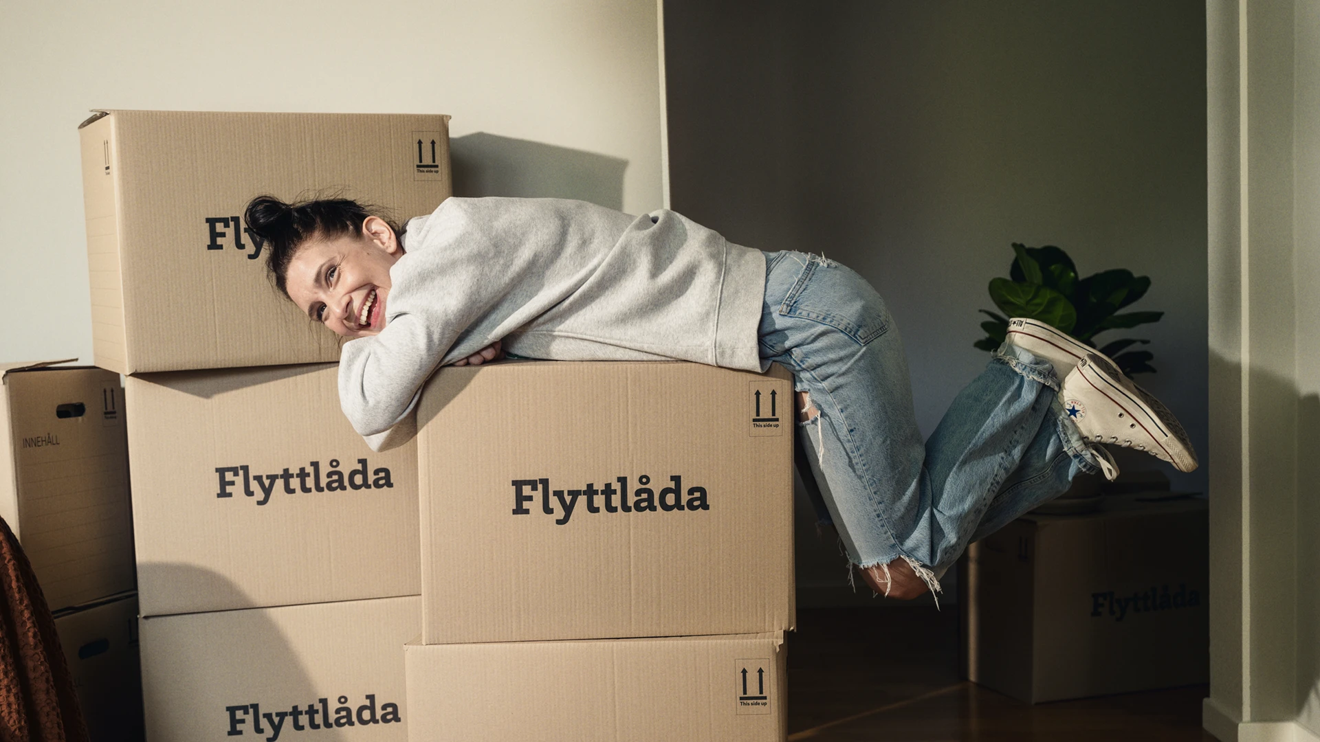 Kvinna ligger på flyttlådor och ler