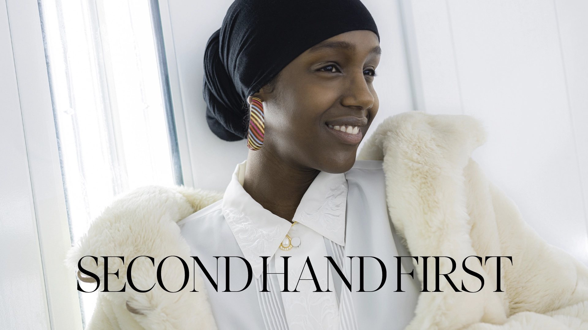Woman in a white room, white fur coat, white blouse. Black text "Second hand first"
