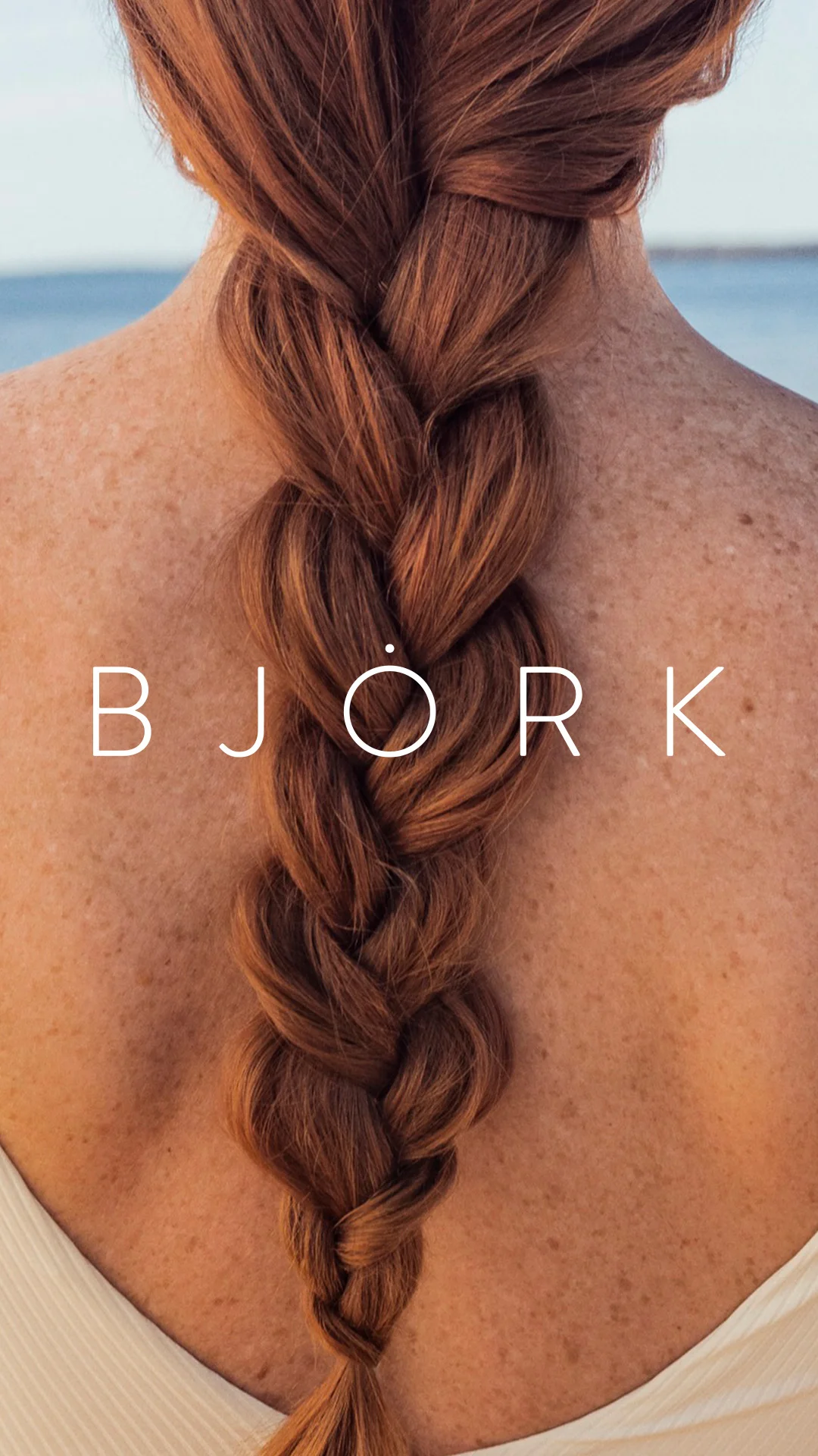 Centrerad rygg-axlar parti på en kvinna med fläta som går ned längs ryggen och björk logotypen i mitten