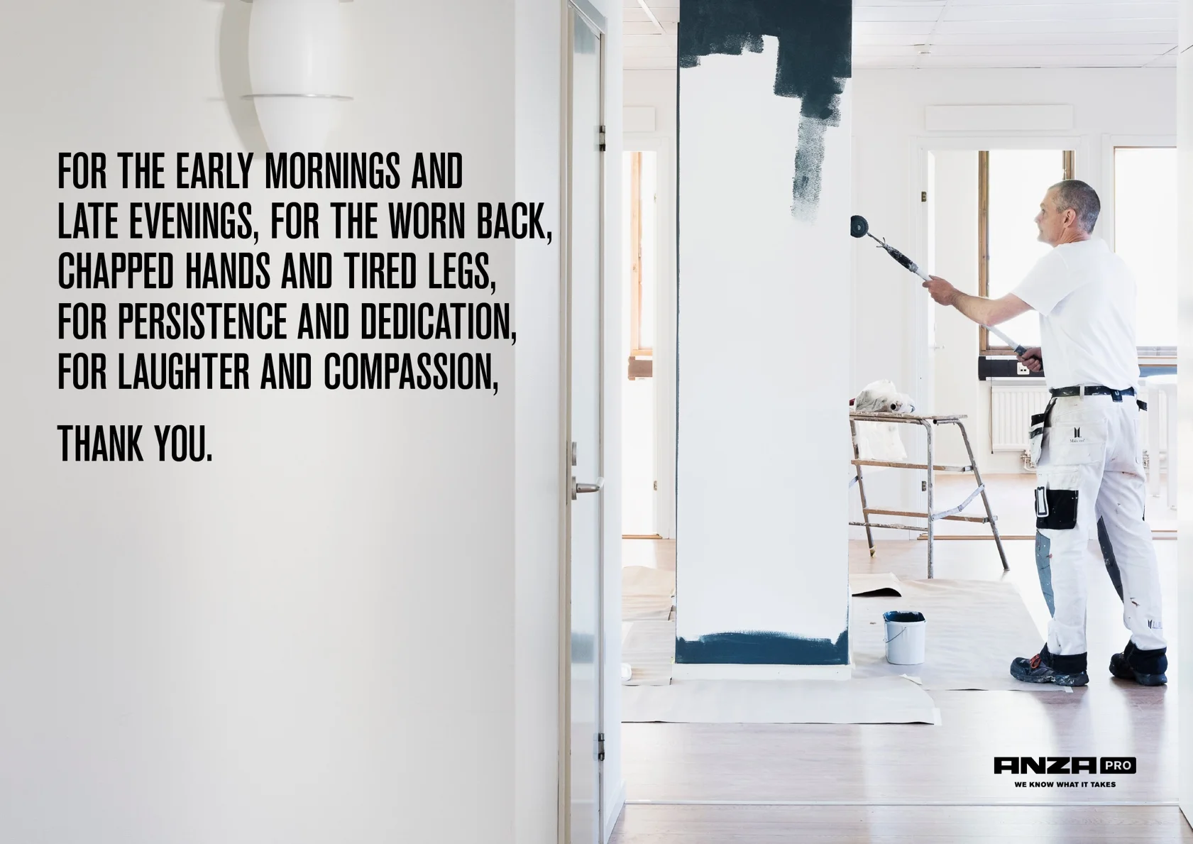 Målargubbe med lång roller målar en vägg vit