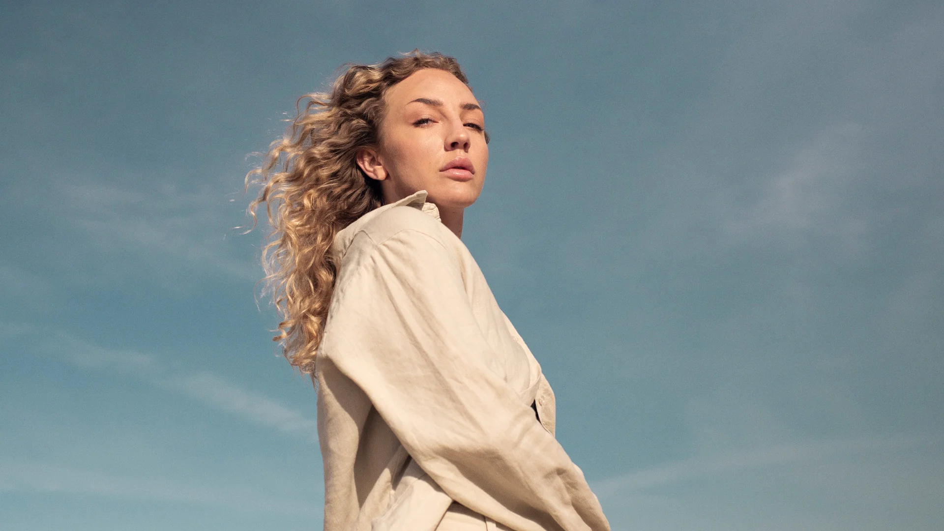 Kvinna i kvällssol som kollar mot horisonten _ Ny Studio