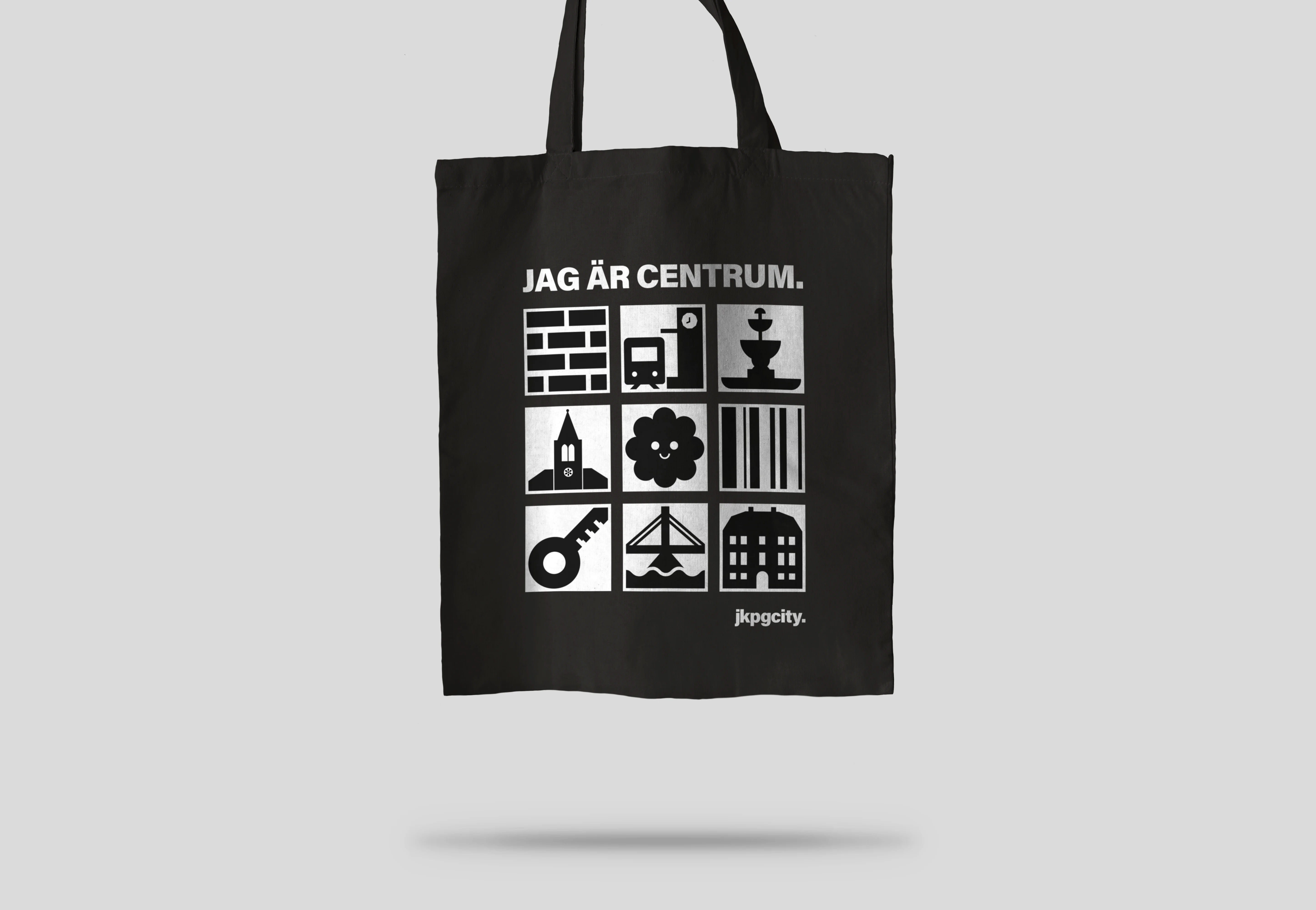 Svart tygkasse med vitt tryck på. Olika ikoner från JKPG citys grafiska profil och texten "jag är centrum"