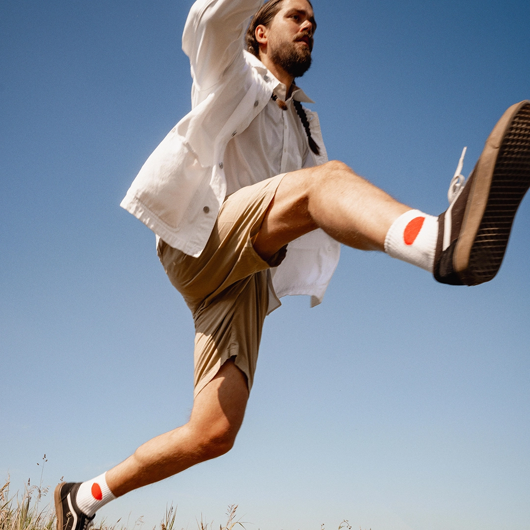 Man in white shirt jumping with the sky as background - Ny Studio