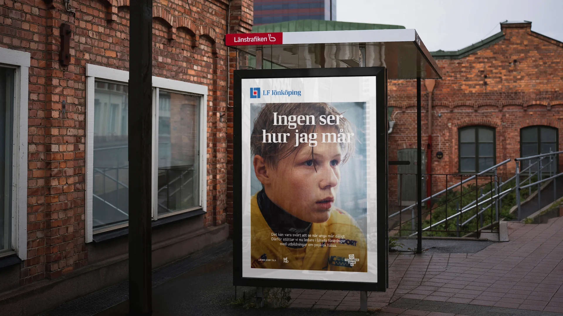 Bild på busshållsplats med poster, "ingen ser hur jag mår" vit text över en bild på svettig kille som precis spelat hockey.
