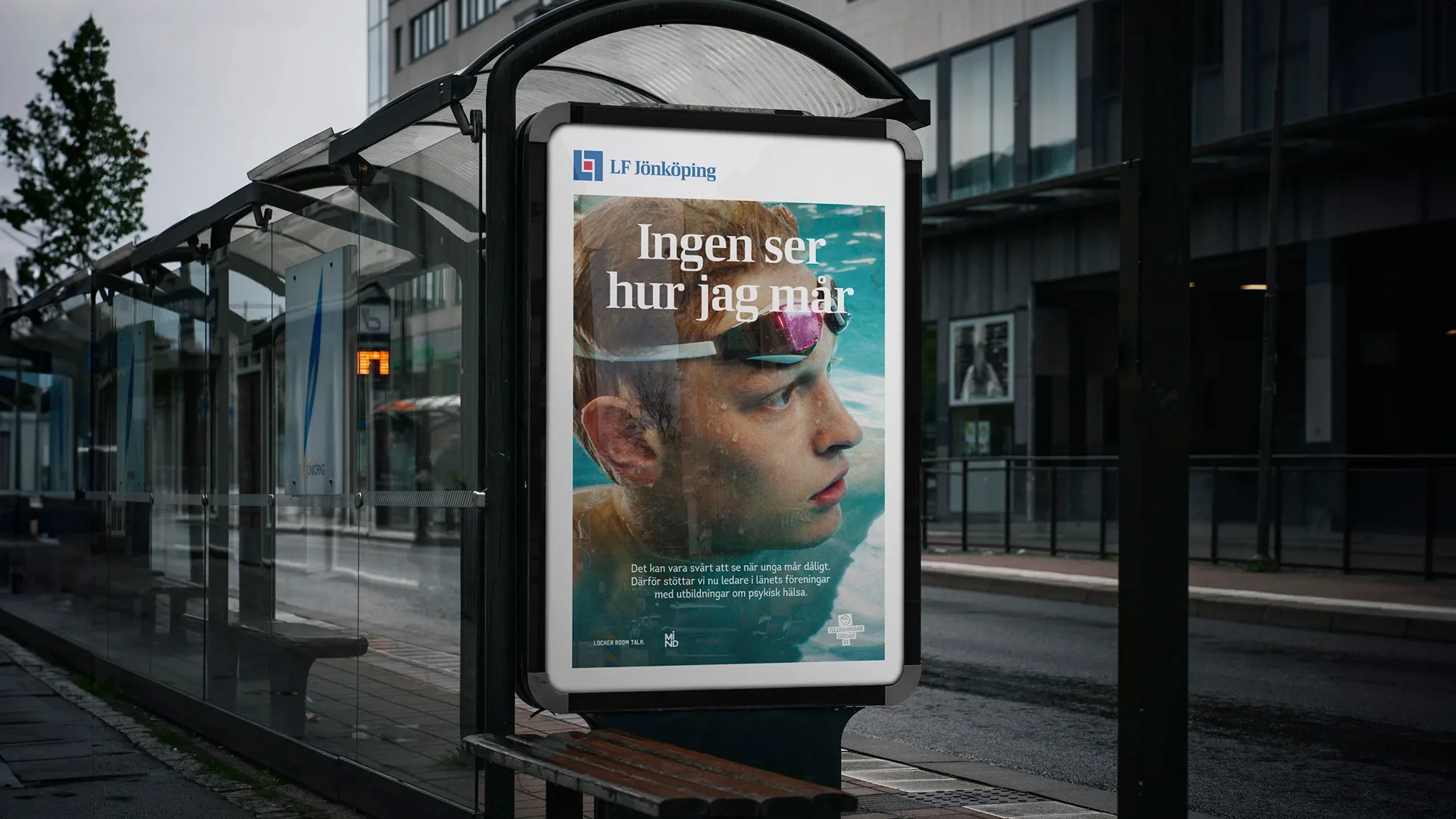 Bild på busshållsplats med poster, "ingen ser hur jag mår" vit text över en bild på kille som har simglasögon och är i en pool.