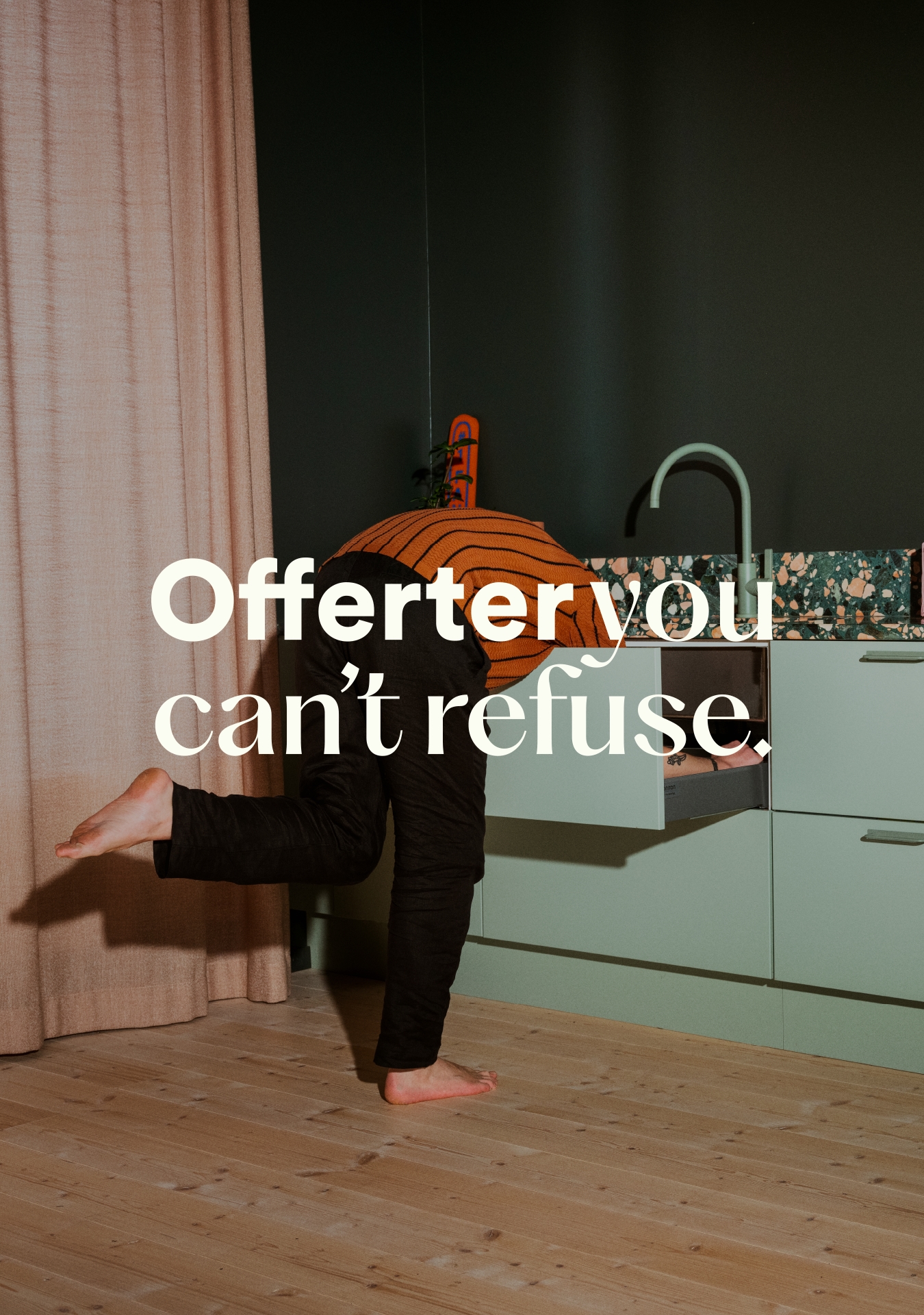 Man i orange tröja sträcker sig ned i en kökslåda